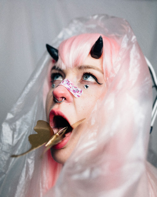 a person with a pink wig and a white mask with a cigarette in the mouth