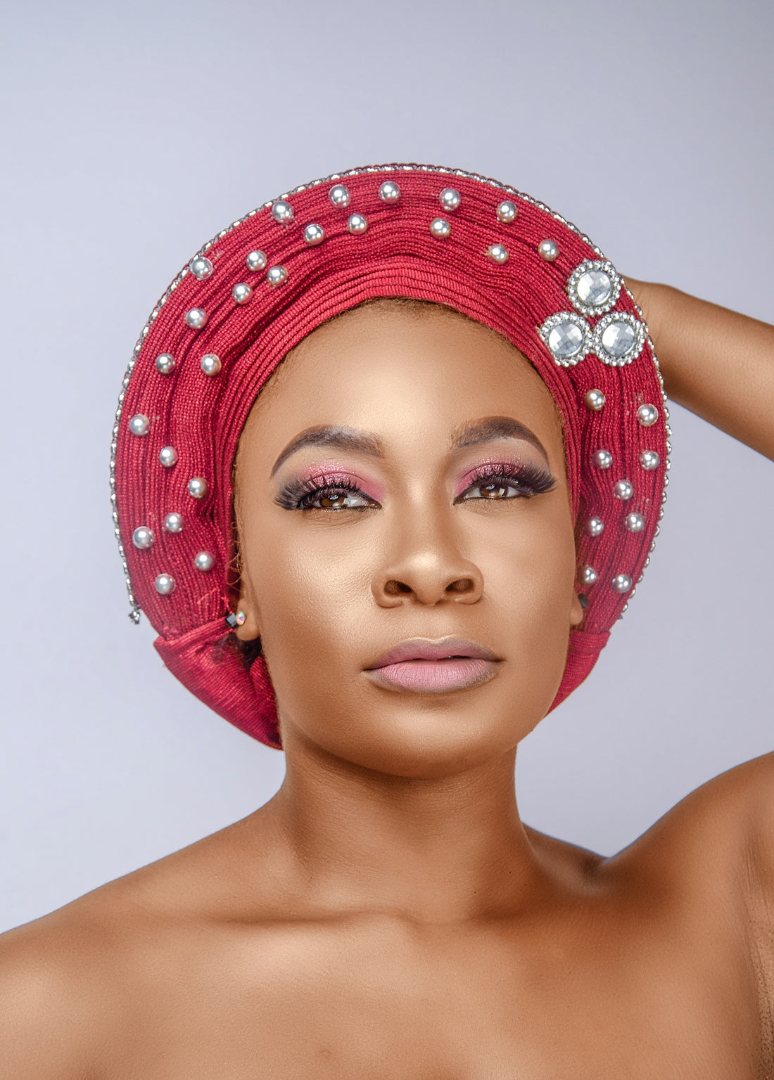 a woman wearing a red turban with pearls on it