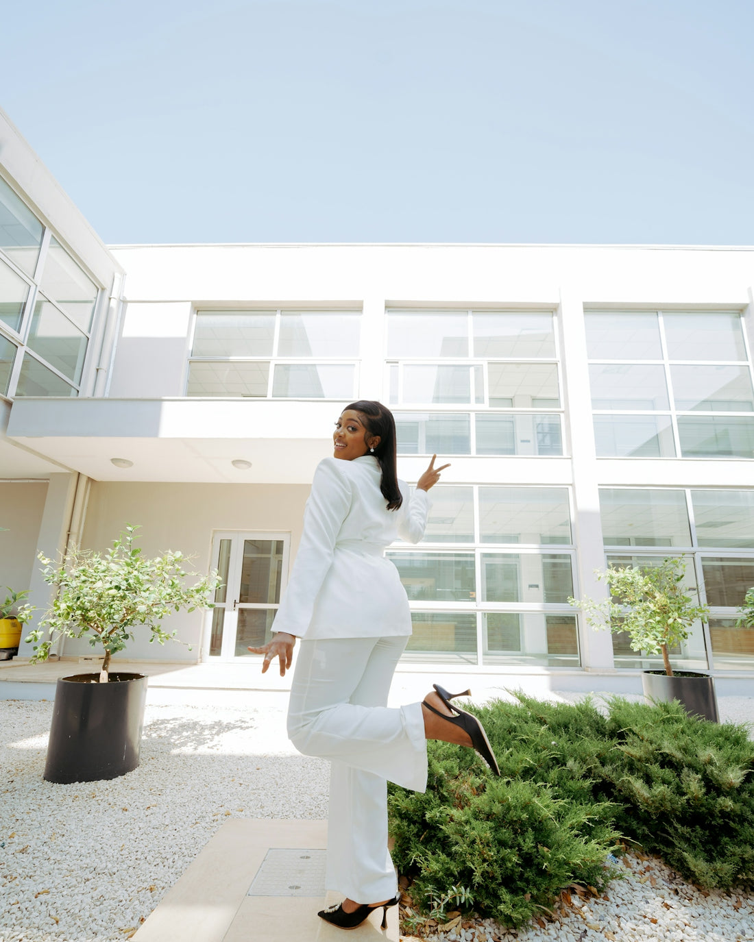 A woman standing in front of a large white building