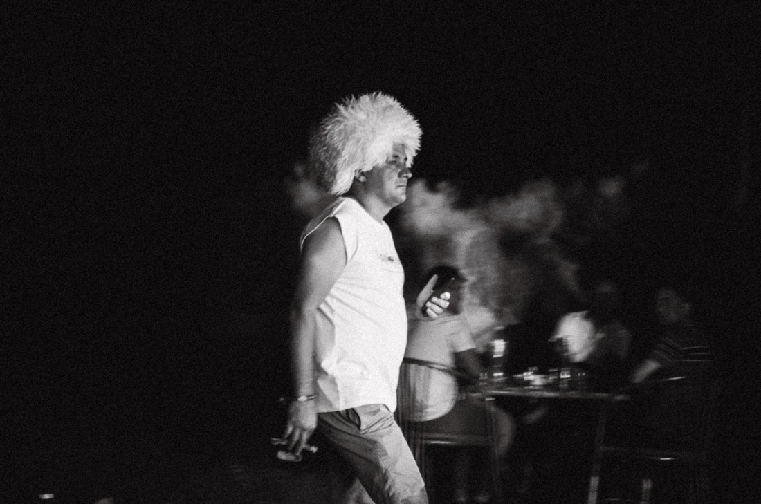 Man with large white wig smoking outdoors at night