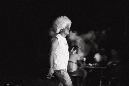 Man with large white wig smoking outdoors at night