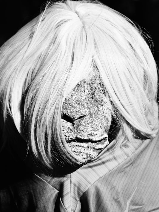 Stone face with white wig and striped shirt.