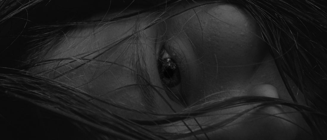 Close-up of a person's eye with dark hair.