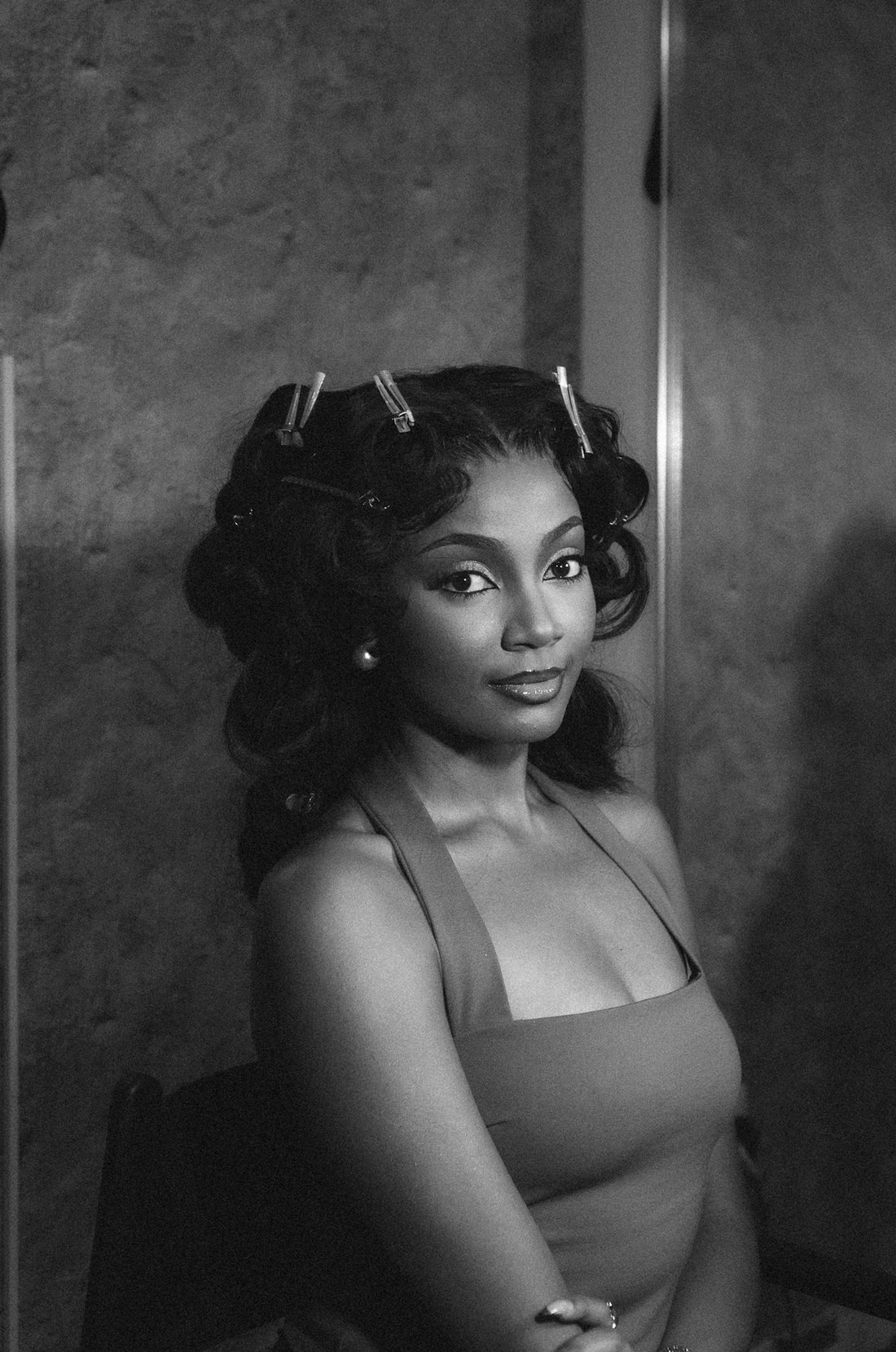 A woman with curlers in her hair looks forward.