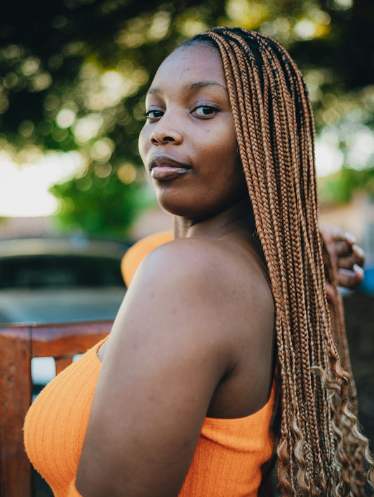 A young woman with braided hair looks over her shoulder.