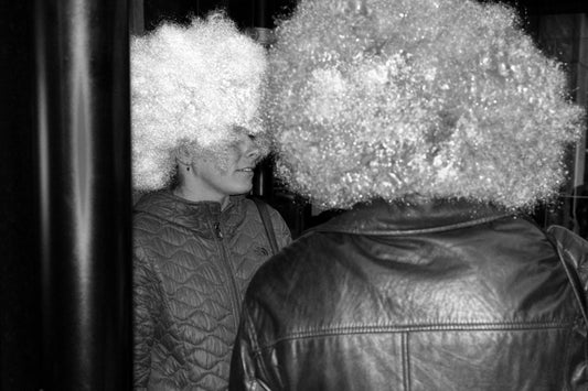 Two people wearing large afro wigs