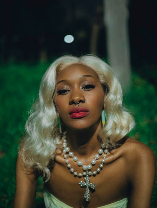 Blonde woman wearing pearls and a nose ring at night.
