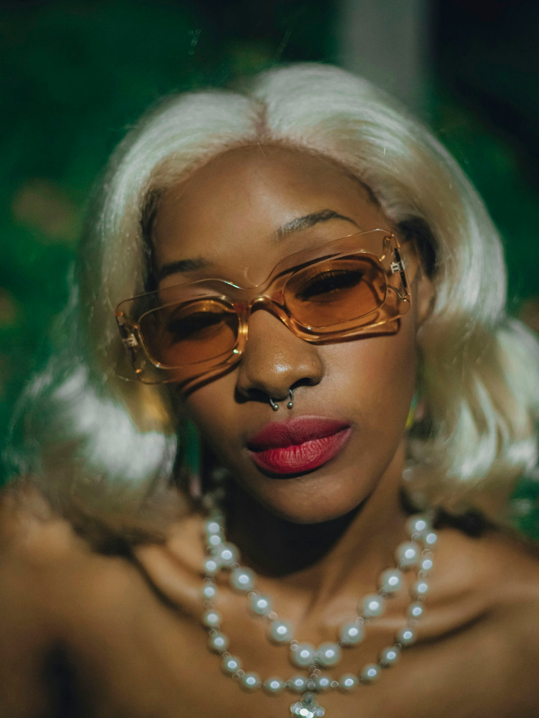 Blonde woman wearing sunglasses and a pearl necklace.